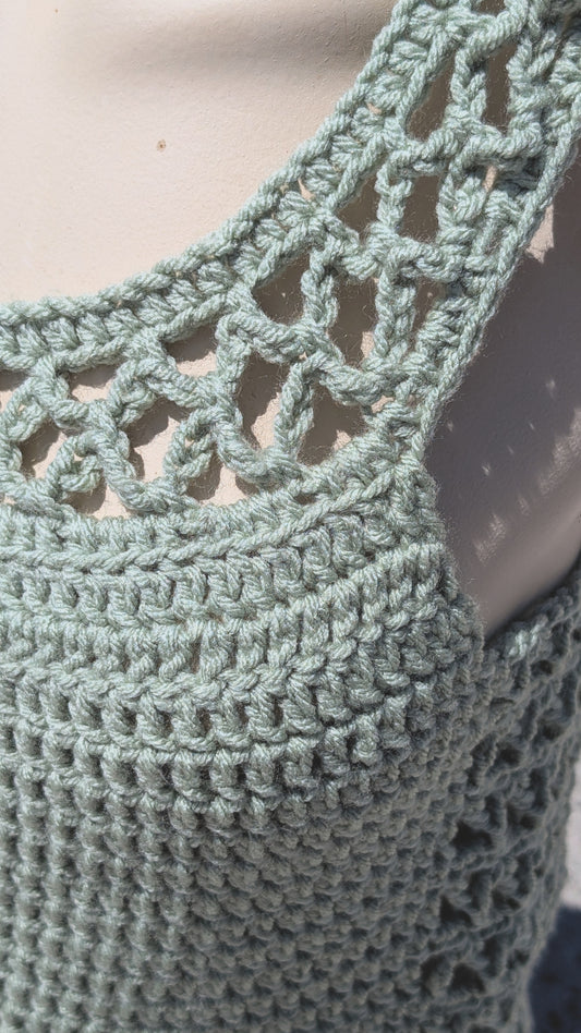 Close-up of a green crochet garment with intricate patterns.