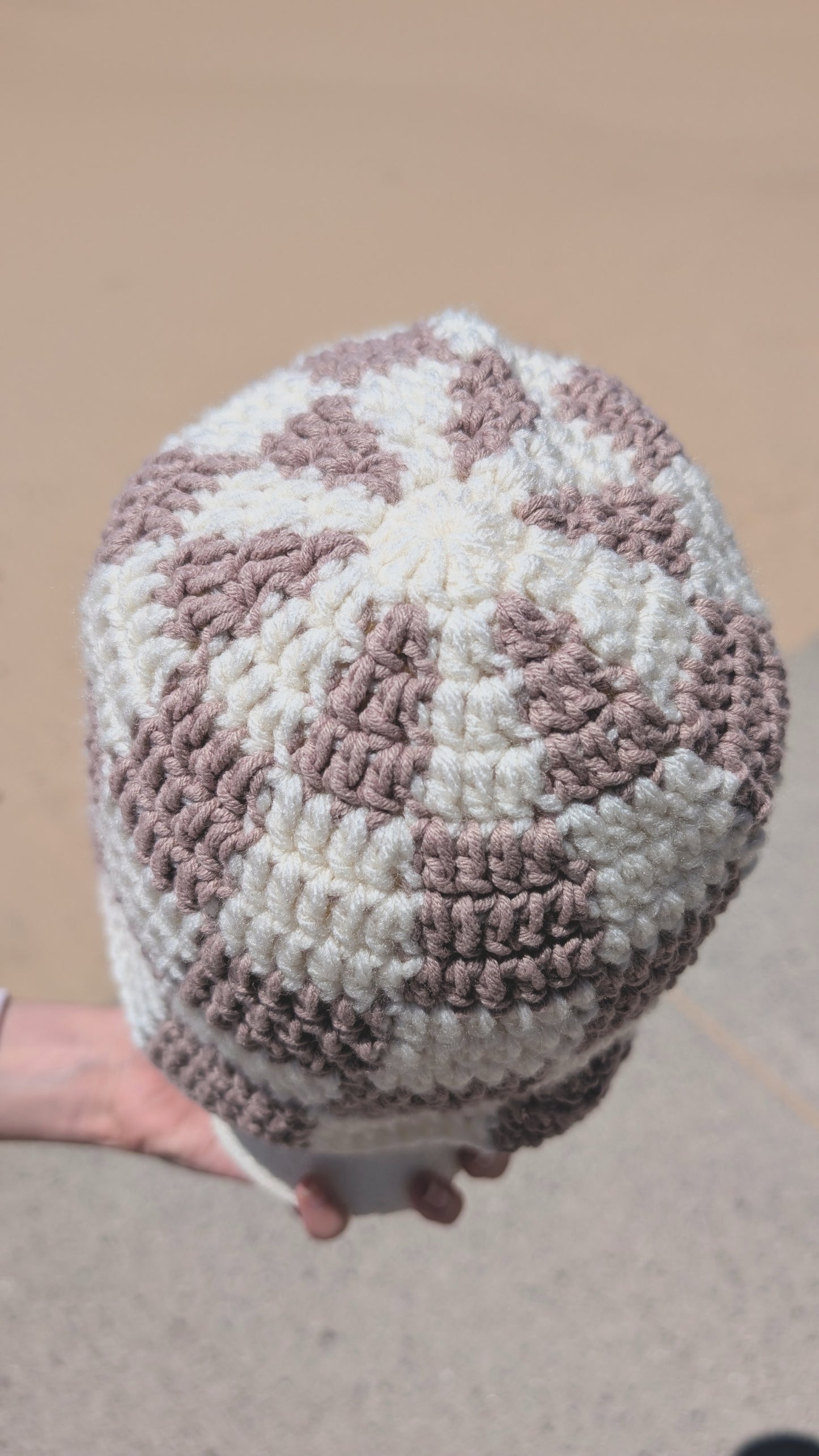 Handmade crochet hat with a pattern held against a plain background