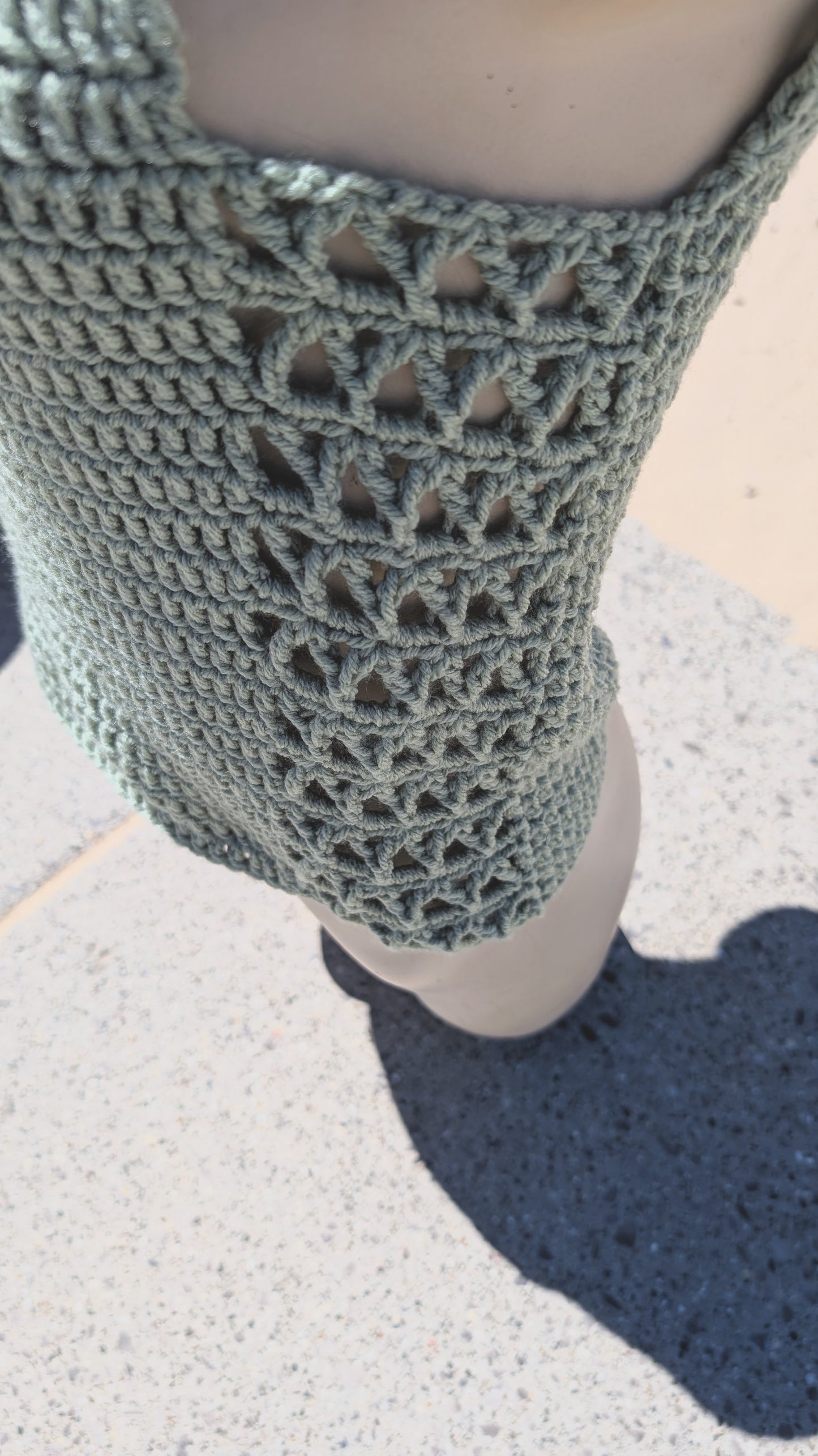Close-up of a mannequin wearing a textured green crochet sleeveless top.