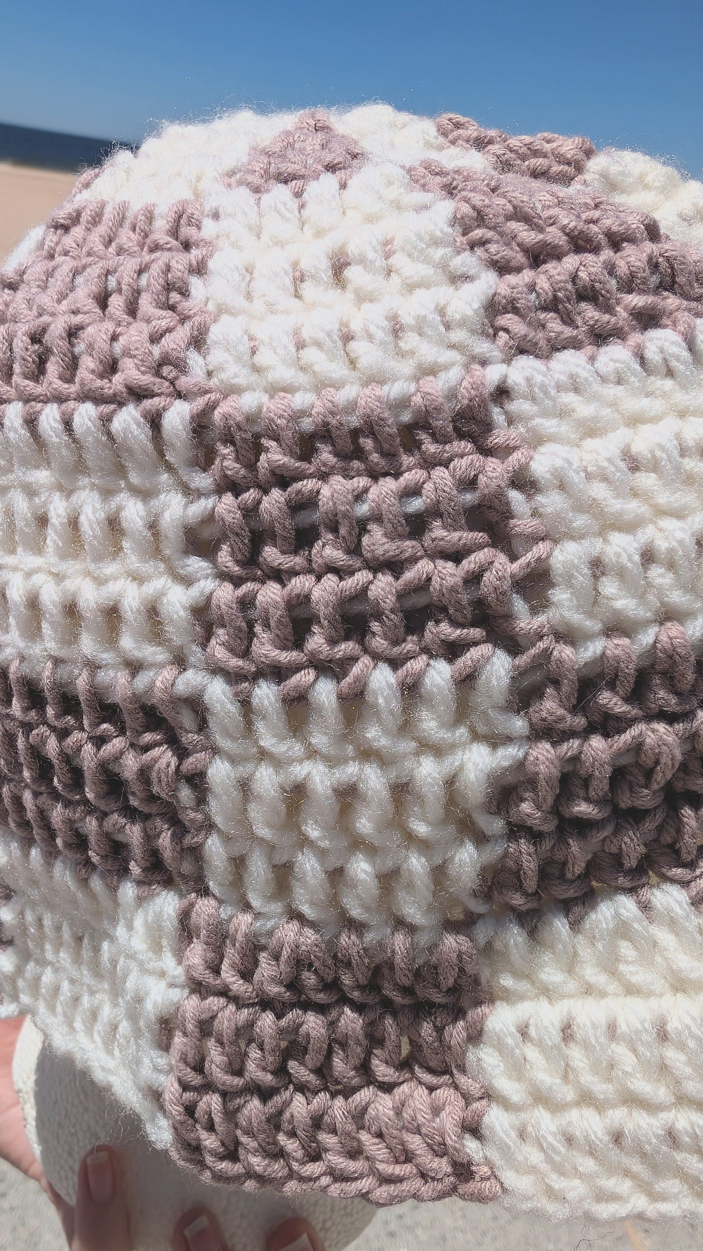 Close-up of a crocheted patterned bucket hat with pink and sand colors.