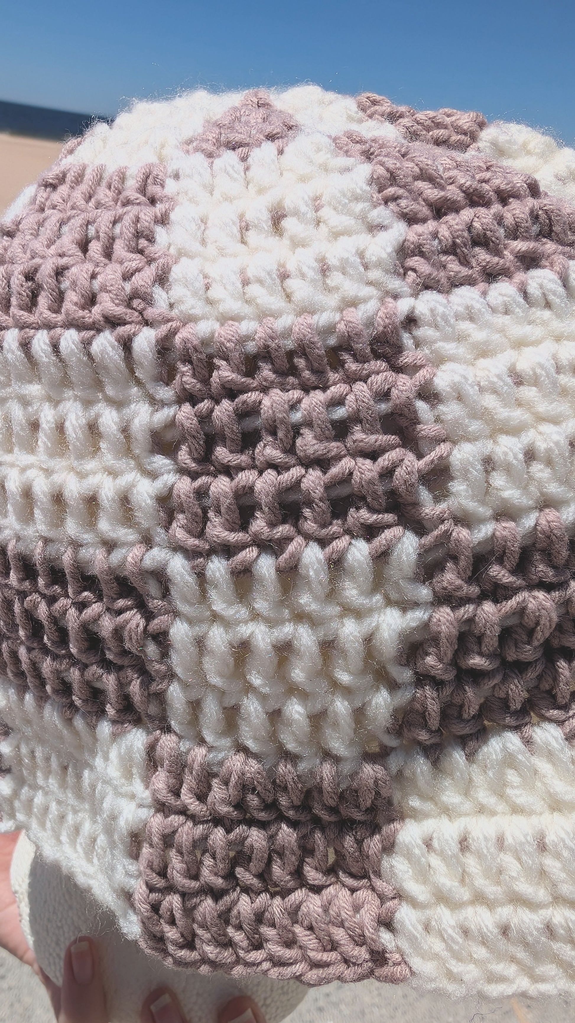 Close-up of a crocheted patterned bucket hat with pink and sand colors.
